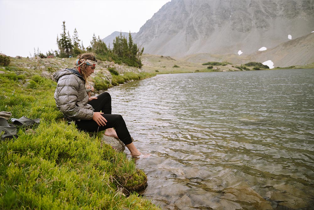Man sitting near lake with feet resting in the water
