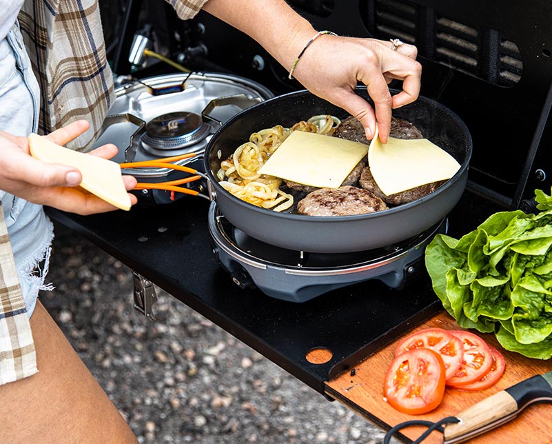 Adding cheese to burgers cooked on the Jetboil Genesis Basecamp System