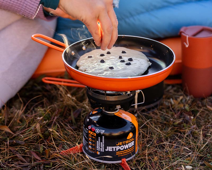 Adding blueberries to a pancake cooked on the Jetboil Summit Skillet and MiniMo Burner
