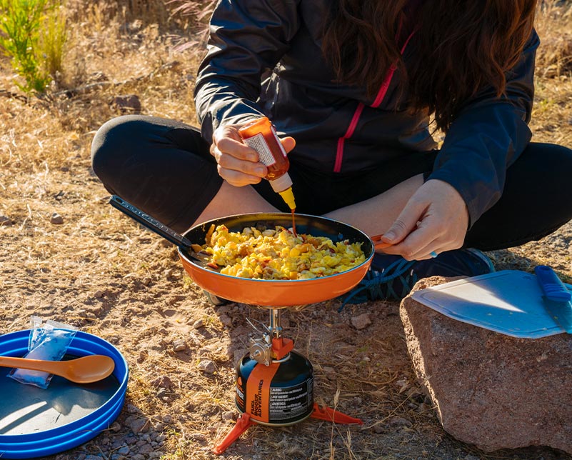 Adding hot sauce to a breakfast meal cooked in the Jetboil Summit Skillet