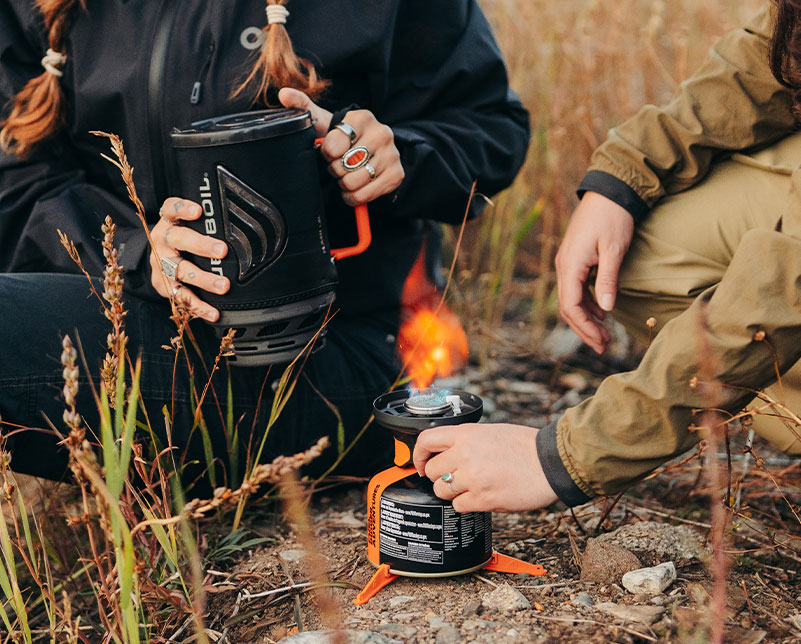 Lit Jetboil Flash 1.8L burner with cook pot in hand ready to place on burner
