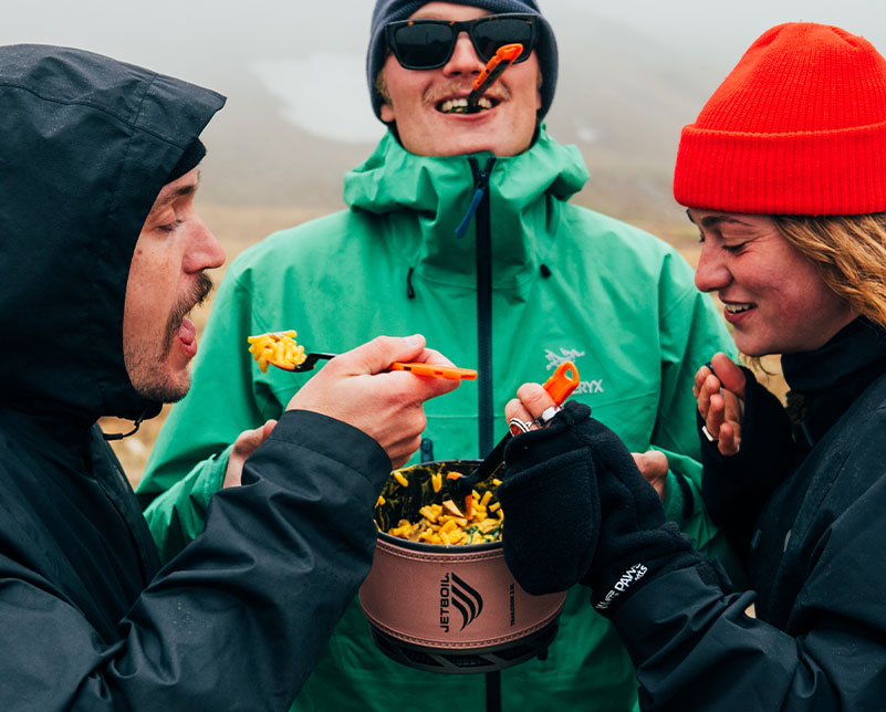 Friends gathered and eating from a Jetboil TrailCook 2.0L Precision Cook System