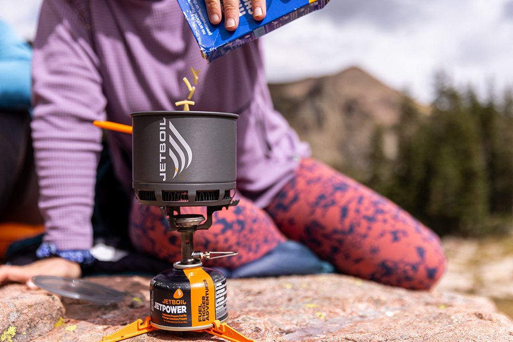 A hiker adds macaroni to a Jetboil Stash.