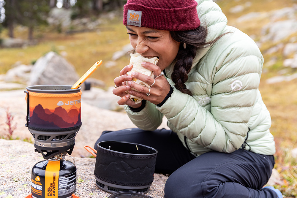 A woman chows down on a camp burrito.