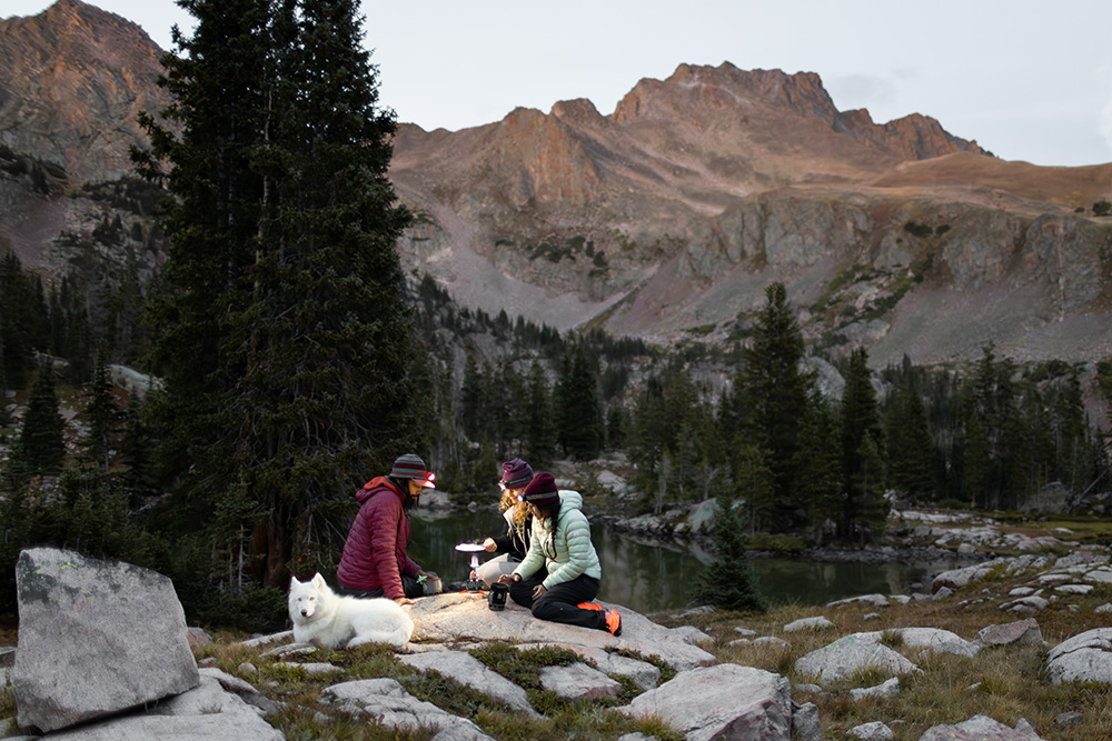 Three campers making dinner on their Jetboils on a rocky mountainside.