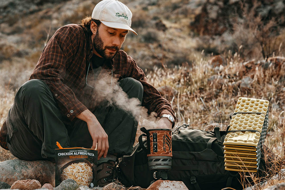 Man watching steam pouring out of Jetboil Zip 0.8L cooking system in duck camo while out in the wild