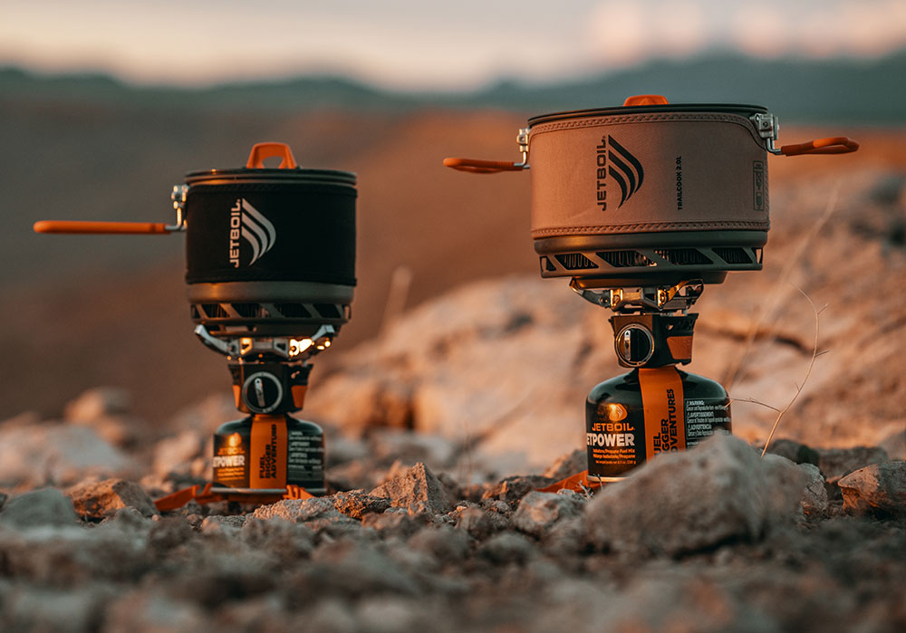 Jetboil TrailCook 1.2L and TrailCook 2.0L Cooking systems side by side with a mountainous backdrop