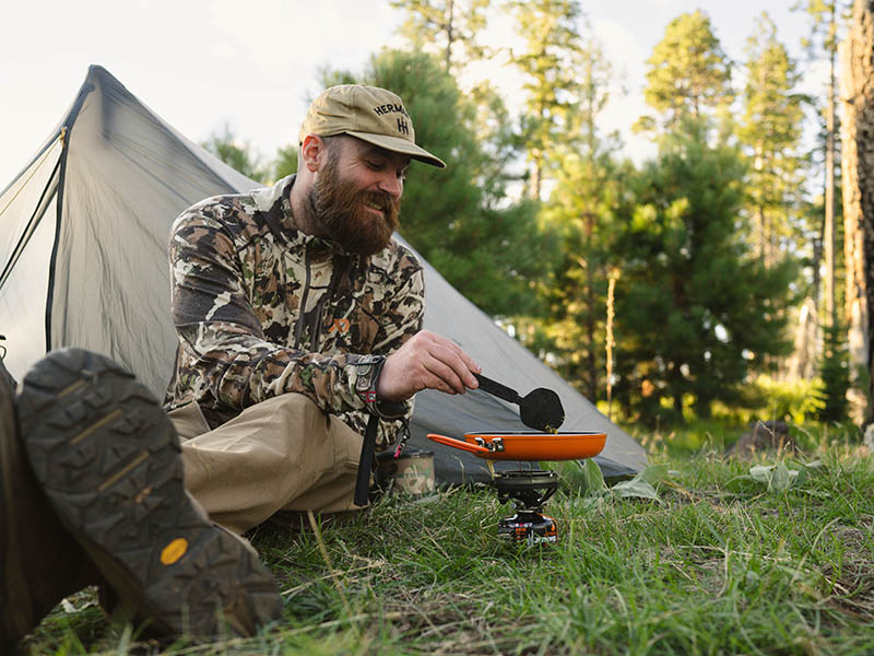 A hunter cooks food in a Summit Skillet on a Jetboil Flash burner.