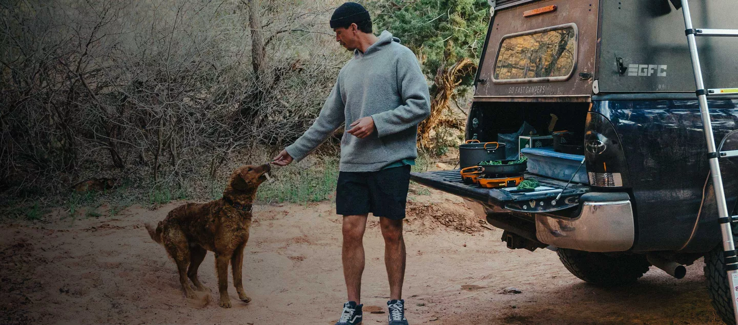 Man feeding dog while cooking on the Jetboil Genesis Basecamp System