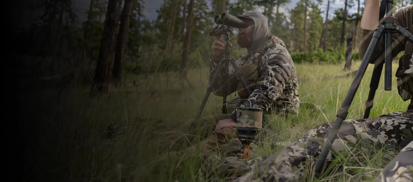 A hunter glasses from a grassy slope.