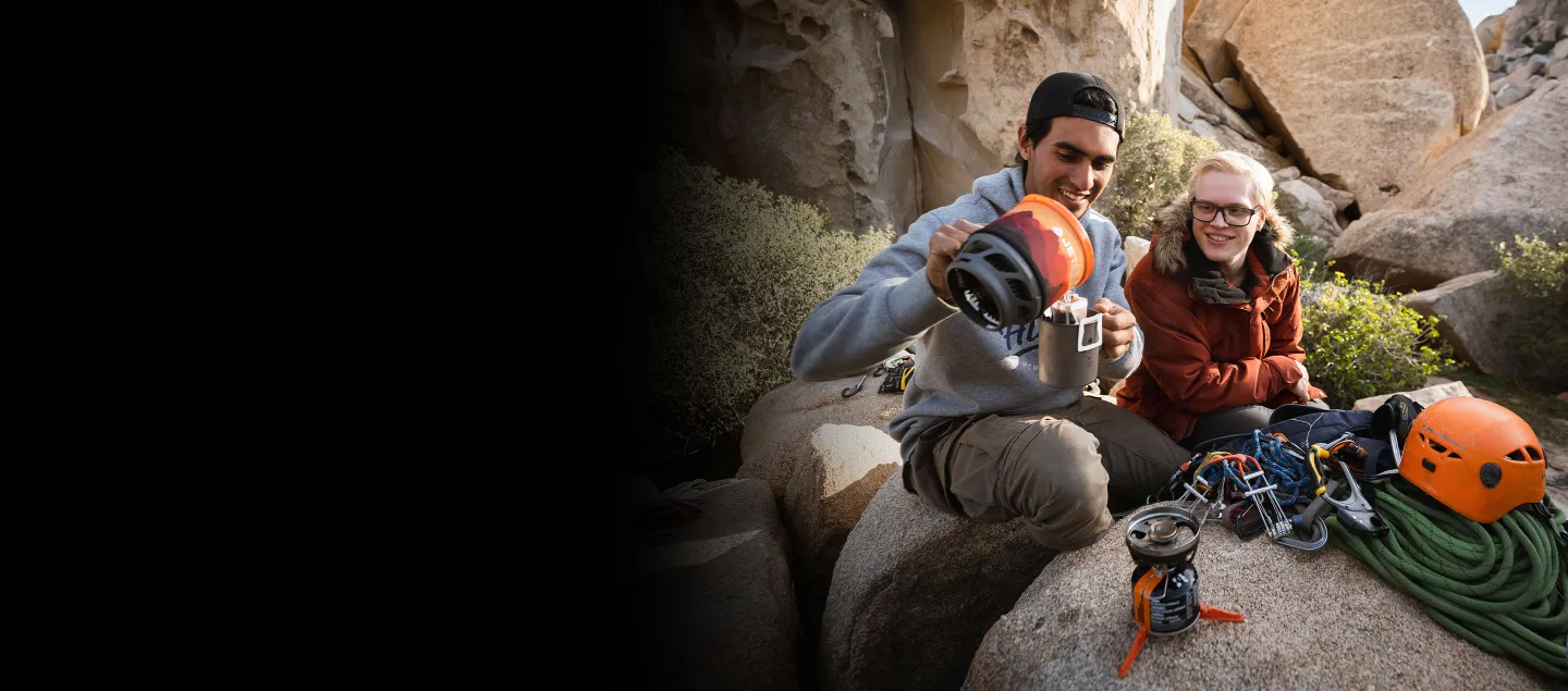 Two men hiking mountains and pouring hot water from the Jetboil MiniMo into cup for coffee