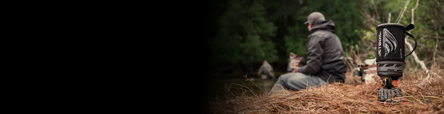 Man sitting off near riverbank with Jetboil Flash 1.0L cooking system in forefront