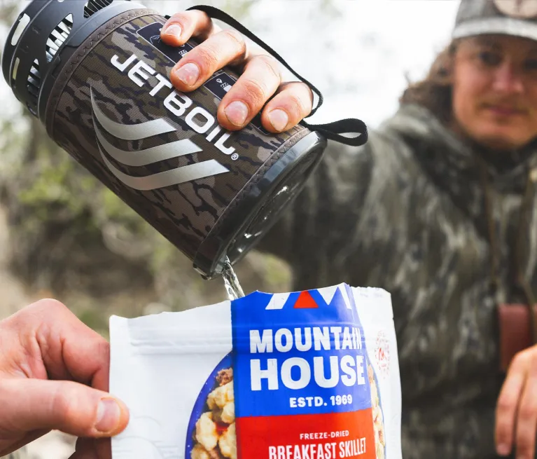 Man pouring hot water from Jetboil Flash 1.0L Fast Boil System in Bottomland into freeze-dried meal while on hunting trail