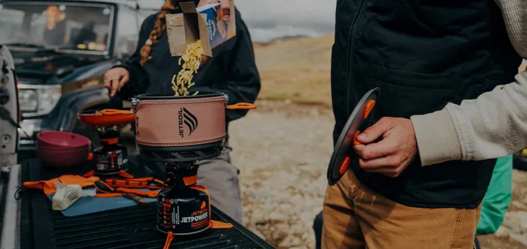 Holding lid in hand and pouring macaroni into the Jetboil TrailCook 2.0L precision cook system