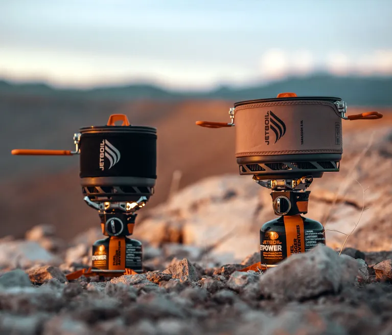 Jetboil TrailCook 1.2L and 2.0L precision cook systems side by side with a rocky mountainous background
