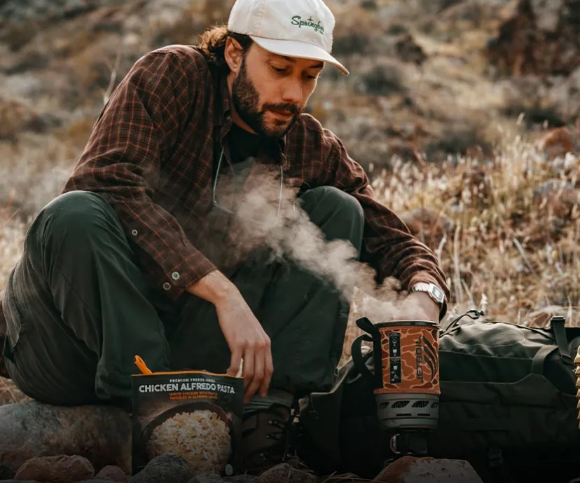 Man with steam rolling out of a Jetboil Zip 0.8L fast boil system ready to eat a freeze dried meal